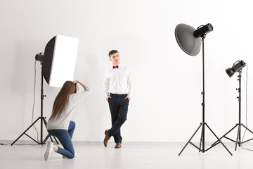 Young man posing for professional photographer on white background in studio