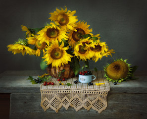 Still life with sunflowers in basket and cherry on darck background