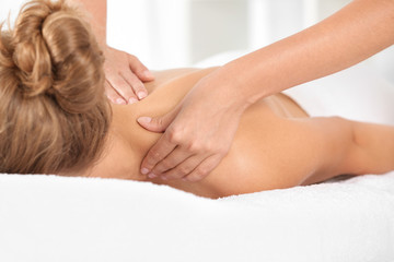 Relaxed woman receiving shoulders massage in wellness center