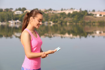 Young woman checking pulse outdoors on sunny day