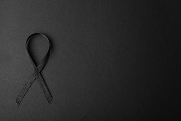Black ribbon and space for text on dark background, top view. Funeral accessory