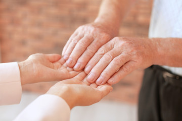 Fototapeta na wymiar Helping hands on blurred background, closeup. Elderly care concept