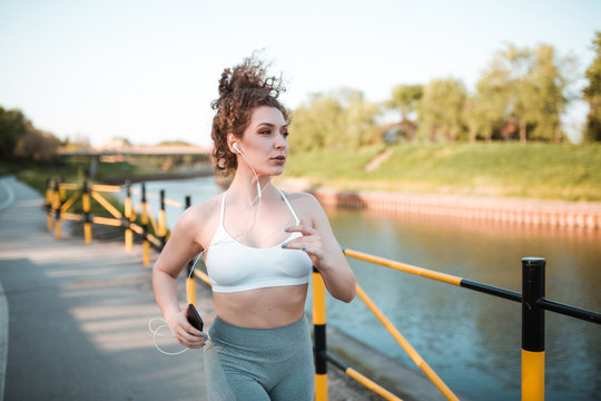 Young female athlete is running outdoors near a river