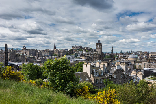 Edinburgh, Scotland, UK - June 13, 2012: Looking from Calton Hill over the town towards the castle under heavy cloudscape. Green and yellow vegetation up front.