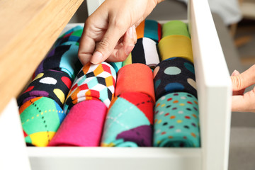 Woman opening drawer with different colorful socks indoors, closeup