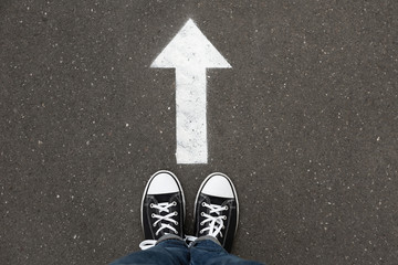 Woman standing near arrow on asphalt, top view. Choice concept