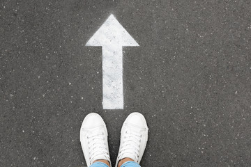 Woman standing near arrow on asphalt, top view. Choice concept © New Africa