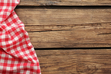 Checkered picnic tablecloth on wooden background, top view
