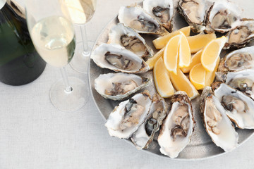 Fresh oysters with cut juicy lemon served on table, above view