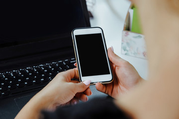 Close-up on the hands of a woman holding a mobile phone with a blank screen. Woman checks information, on the phone, shopping online. Technology development concept.