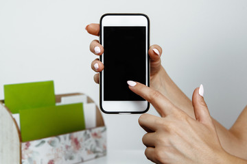 Telephone in hand. The woman is holding a white telephone in hands with a blank display. The girl holds the phone with his finger, the concept of completing the content.