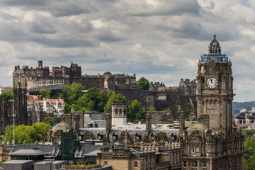 Fototapeta na wymiar Edinburgh, Scotland, UK - June 13, 2012: Looking from Calton Hill upon the Balmoral Clock Tower along Princess street and the Castle under Heavy Cloudscape.