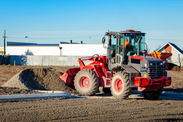 Fototapeta premium A red loader used at a building site to shift piles of gravel and dirt 
