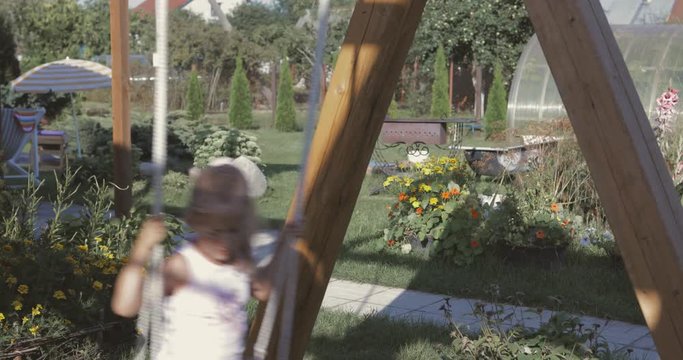 Little girl having fun on a swing outdoor. 4k video shooting by handheld gimbal
