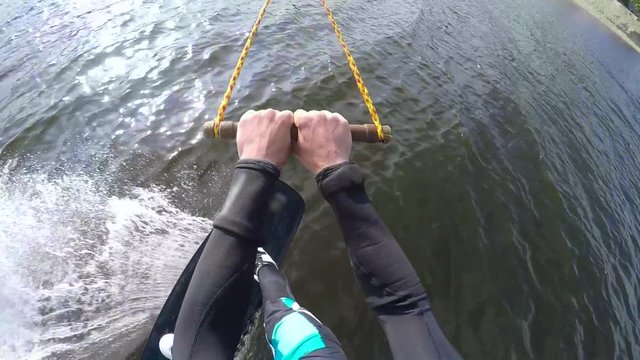 Sports guy in a wetsuit is riding a wakeboard on the river
