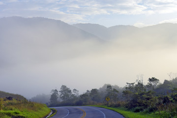 Highway empty with fog, hills and trees