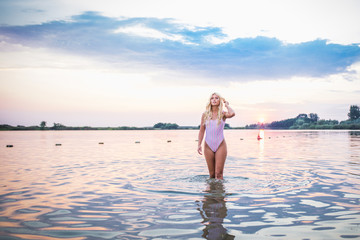 Fototapeta premium Beautiful girl posing in water at sunset