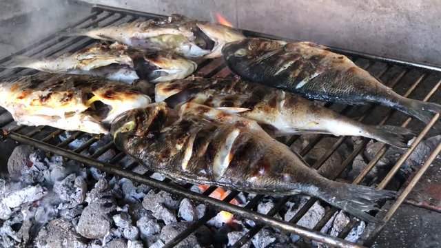 Mediterranean fish on a grill. Summer barbeque fish. Very rustic style. Real fire grill.