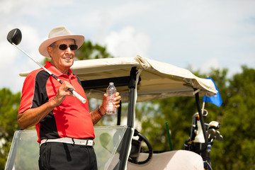 Senior man golfing and drinking water.