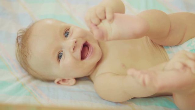 beautiful newborn lying on back looking into camera and smiling.