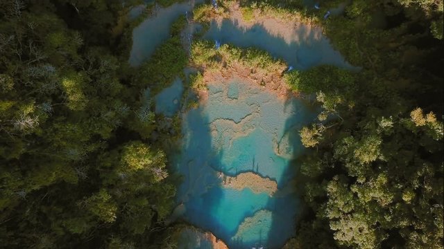 Aerial Zoom Out over Semuc champey pools in the Guatemala forest at sunset
