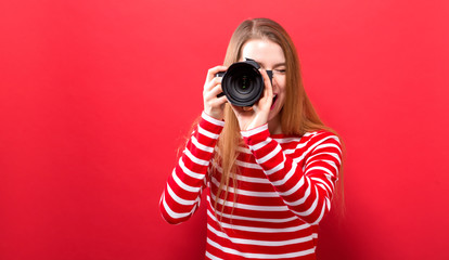Young woman holding a camera on a solid background