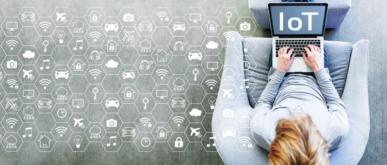 IoT concept with man using a laptop in a modern gray chair