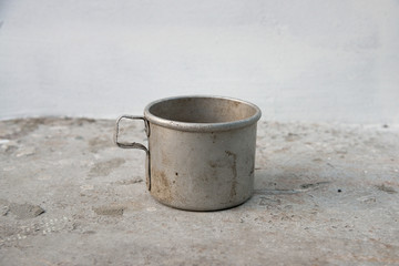 Old aluminum mug on the old grey metal table