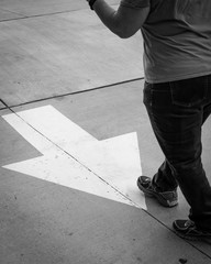 Black and white of woman walking against arrow