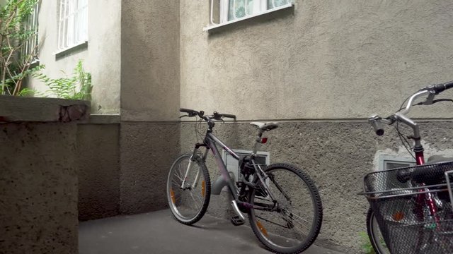 Two parked bicycles within a building complex - panning shot