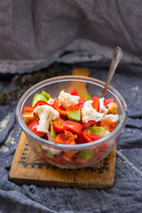 Salad with tomatoes, cauliflower and cucumber. Close up view. On wooden board. Vegetarian and vegan healthy food. Fresh raw vegetables.