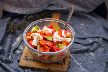 Salad with tomatoes, cauliflower and cucumber. Close up view. On wooden board. Vegetarian and vegan healthy food. Fresh raw vegetables.
