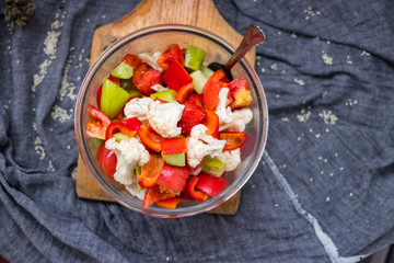 Salad with tomatoes, cauliflower and cucumber. Close up view. On wooden board. Vegetarian and vegan healthy food. Fresh raw vegetables.