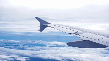 Obraz premium A window view inside an airplane. A wing of a plane over the clouds.