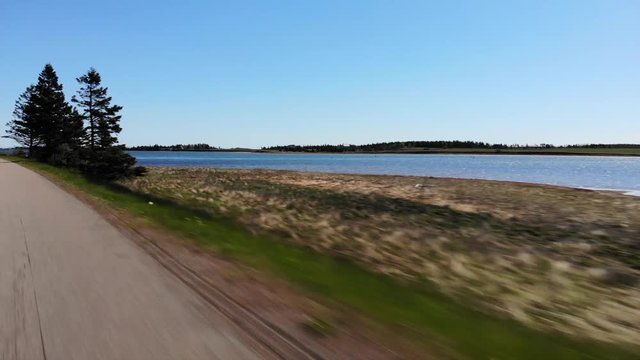 Driving on country road alongside waterfront with fishing boat lift
