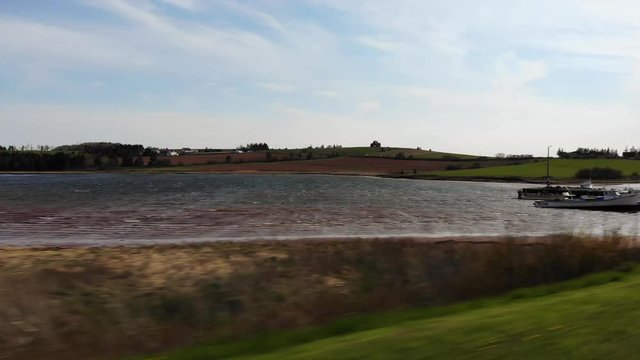 Driving past boats docked at fish market in fishing village