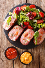 Spicy roast pork brisket and fresh vegetable salad are served ketchup and mustard. Vertical top view