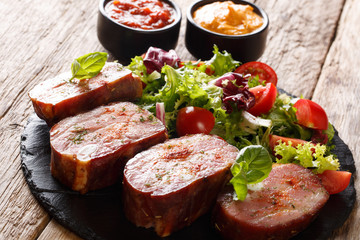 Smoked pork ribs and fresh vegetable salad on a slate plate with ketchup and mustard. horizontal