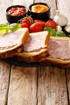 French food: terrine, pate in a brioche with spices, garlic served with vegetables and sauces close-up. vertical