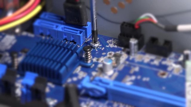 Screwdriver screw bolt on computer motherboard. Computer warranty works