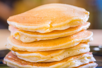 beautiful prepare pancakes for serving process.pancakes made from dough and batter.tasty dessert sweets pancakes served on daylight in cafe background.pancakes on black and white plate.