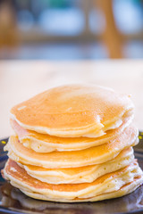 beautiful prepare pancakes for serving process.pancakes made from dough and batter.tasty dessert sweets pancakes served on daylight in cafe background.pancakes on black and white plate.