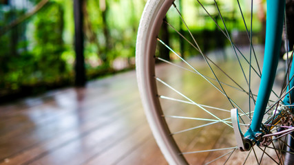 Fototapeta na wymiar Closeup of vintage bicycle front sprocket hub,wheel and pedal, that bicycle parking for decorate in coffee shop, selective focus, blur and bokeh background outdoor concept.