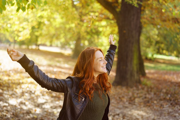 frau breitet lachend die arme aus im wald im herbst