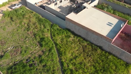 4K Cinematic Aerial footage flying over the top of a team of people building with blocks and hand mixed cement with many vehicles and houses surrounding the site in Porto Seguro, Brazil. - Powered by Adobe