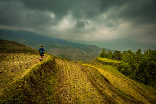 Boy walking along rice terraces near Dazhai, Guangxi, China