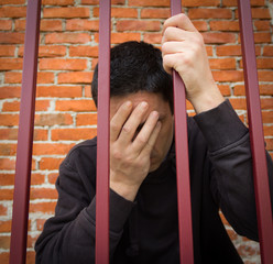 The prisoner behind the bars.Hold with hands on the grids in desperation 