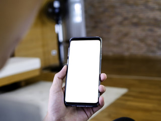 close up of man holding smartphone in hand, relax sitting and using smart phone with blank copy space white screen for graphic application or advertising in cafe or co-working space from top view.