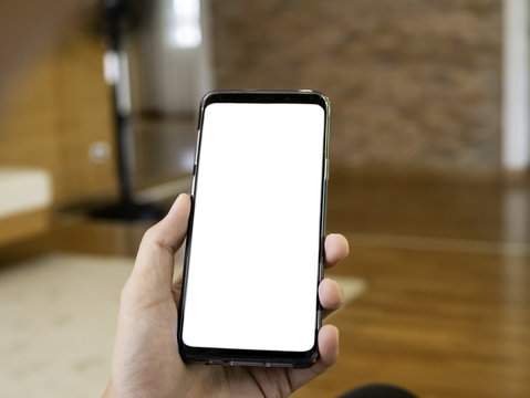 close up of man holding smartphone in hand, relax sitting and using smart phone with blank copy space white screen for graphic application or advertising in cafe or co-working space from top view.