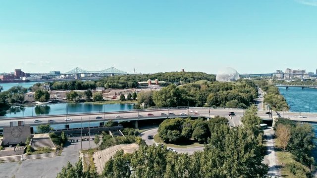 aerial drone footage of montreal with bridges and a park area plus ile sainte helene island with the biosphere dome in the background